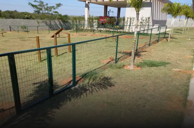 Alambrado verde cercando área gramada
