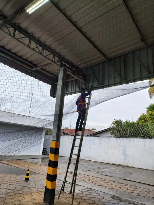 Instalador da Telas Jussara em escada fixando rede de proteção em cobertura
